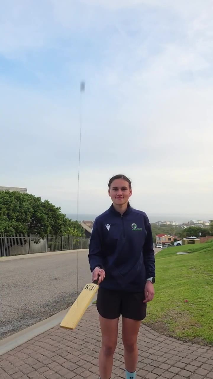 A young cricketer in a driveway holding a KiTi-Bat with the ball on its string