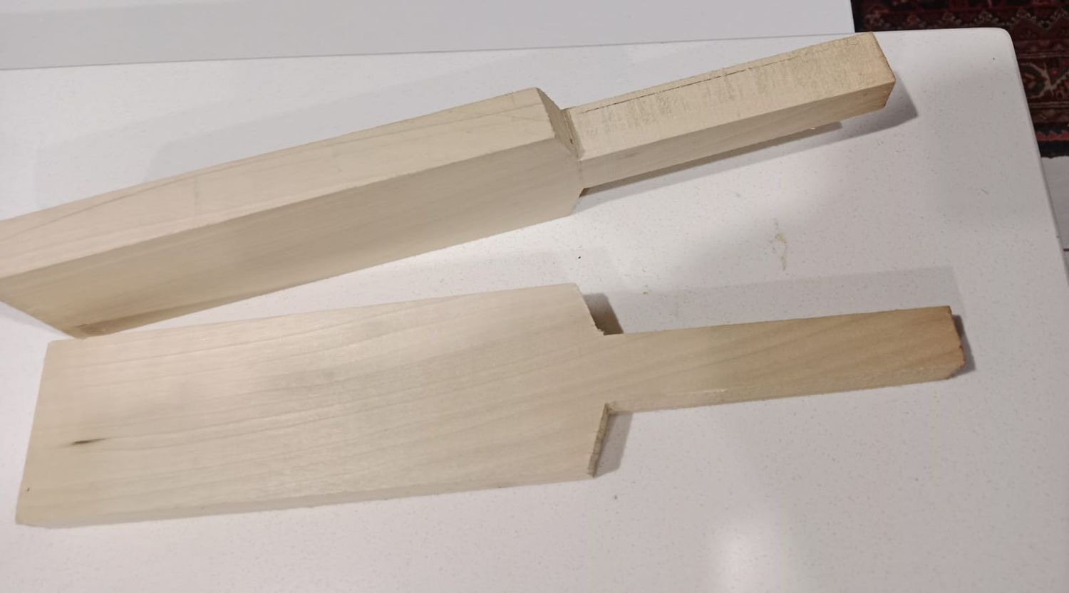 Two bats side by side: one still flat and square, one shaped and rounded