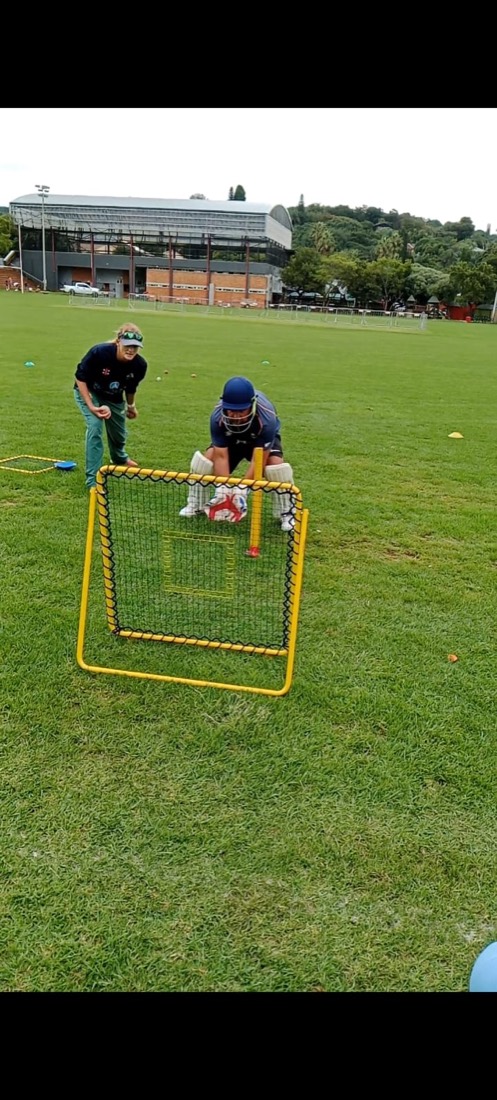Two young cricketers training with the Catch-It rebound net on a field