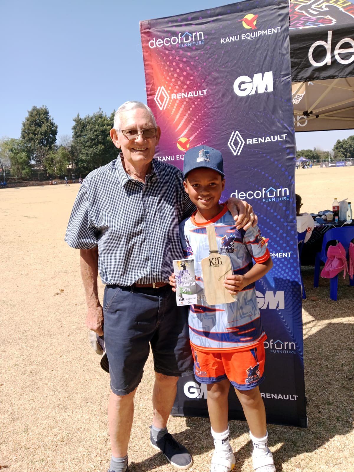 A young cricketer holding an award beside Nico at a club day