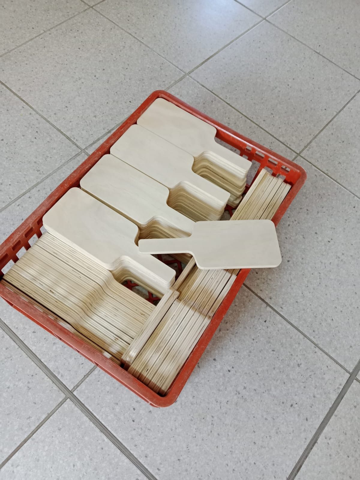 A red crate holding stacked KiTi Junior plywood blanks