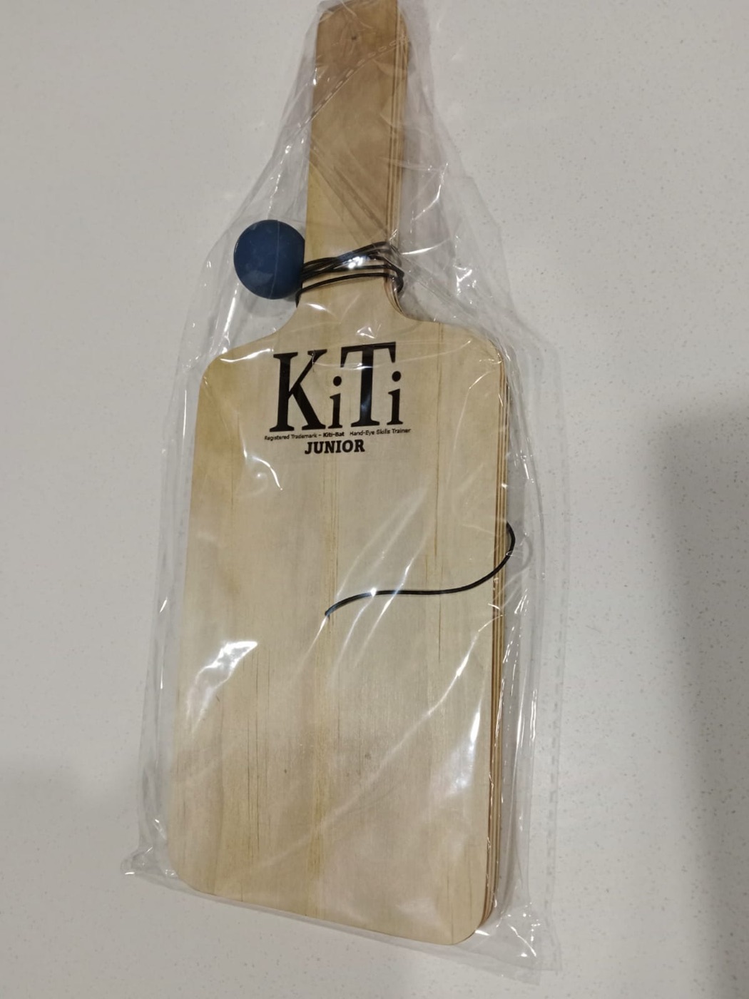 A KiTi Junior in its sleeve, with the blue rubber ball and elastic string attached