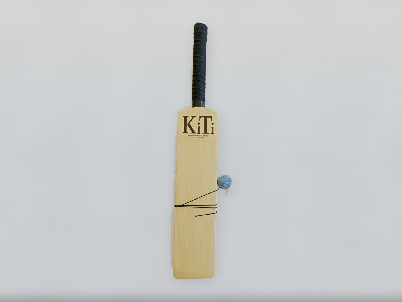 A KiTi-Bat on its own: pale poplar blade with the KiTi mark, black rubber grip and the blue ball on its elastic string